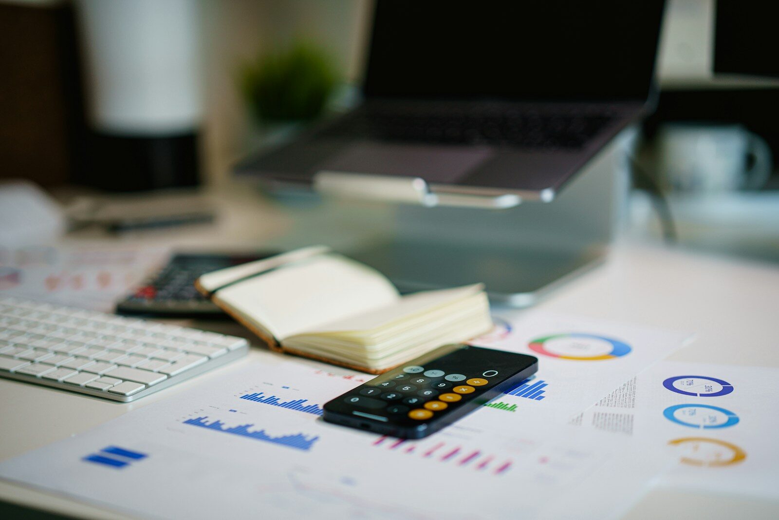 a phone calculator and papers on table next to a laptop